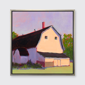 A print of a beige barn, a lavender sky, green bushes and trees and a light green foreground in a silver floater frame hangs on a white wall.
