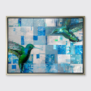 A blue and green abstract hummingbird print in a silver floater frame hangs on a white wall.