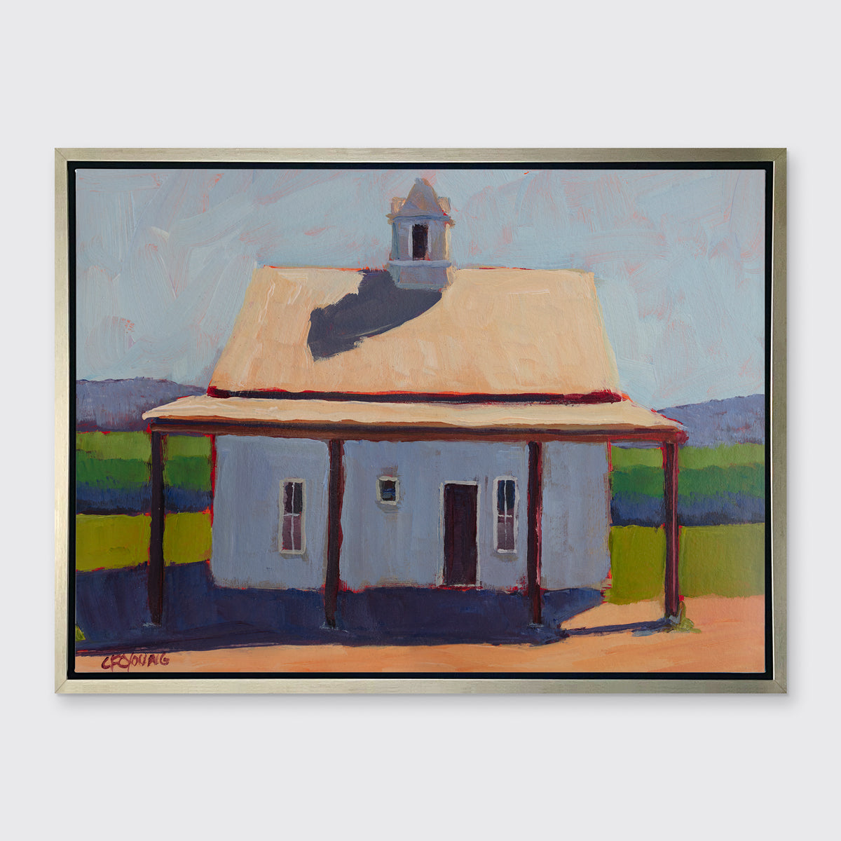 A blue, beige, lavender and green contemporary barn print in a silver floater frame hangs on a white wall.