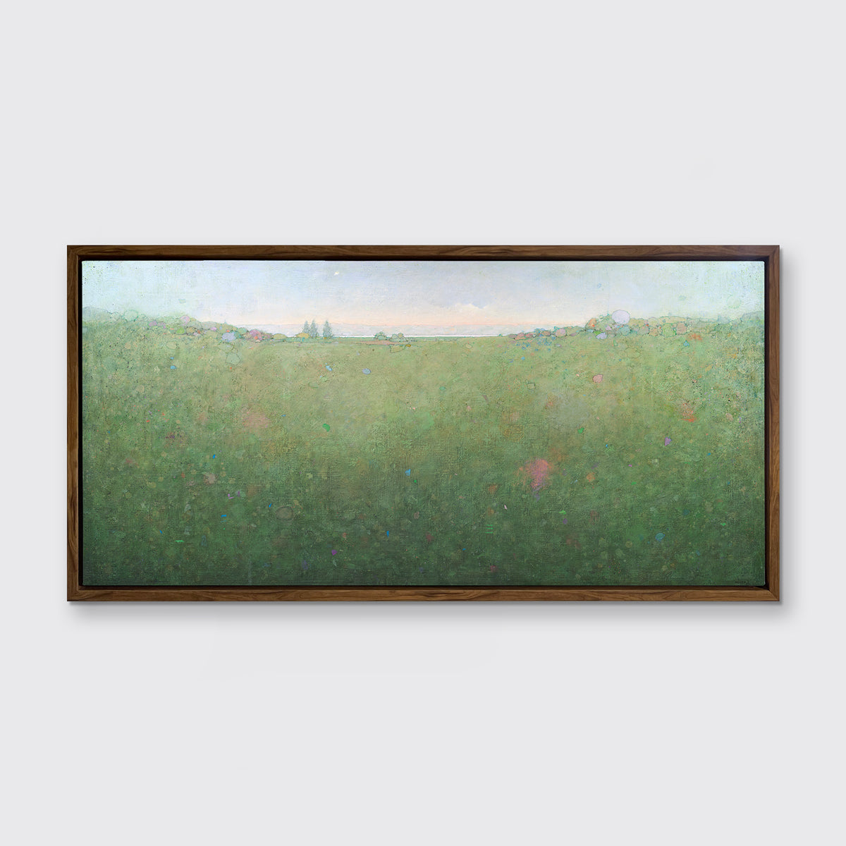 A green abstract landscape print in an oak wood floater frame hangs on a white wall.