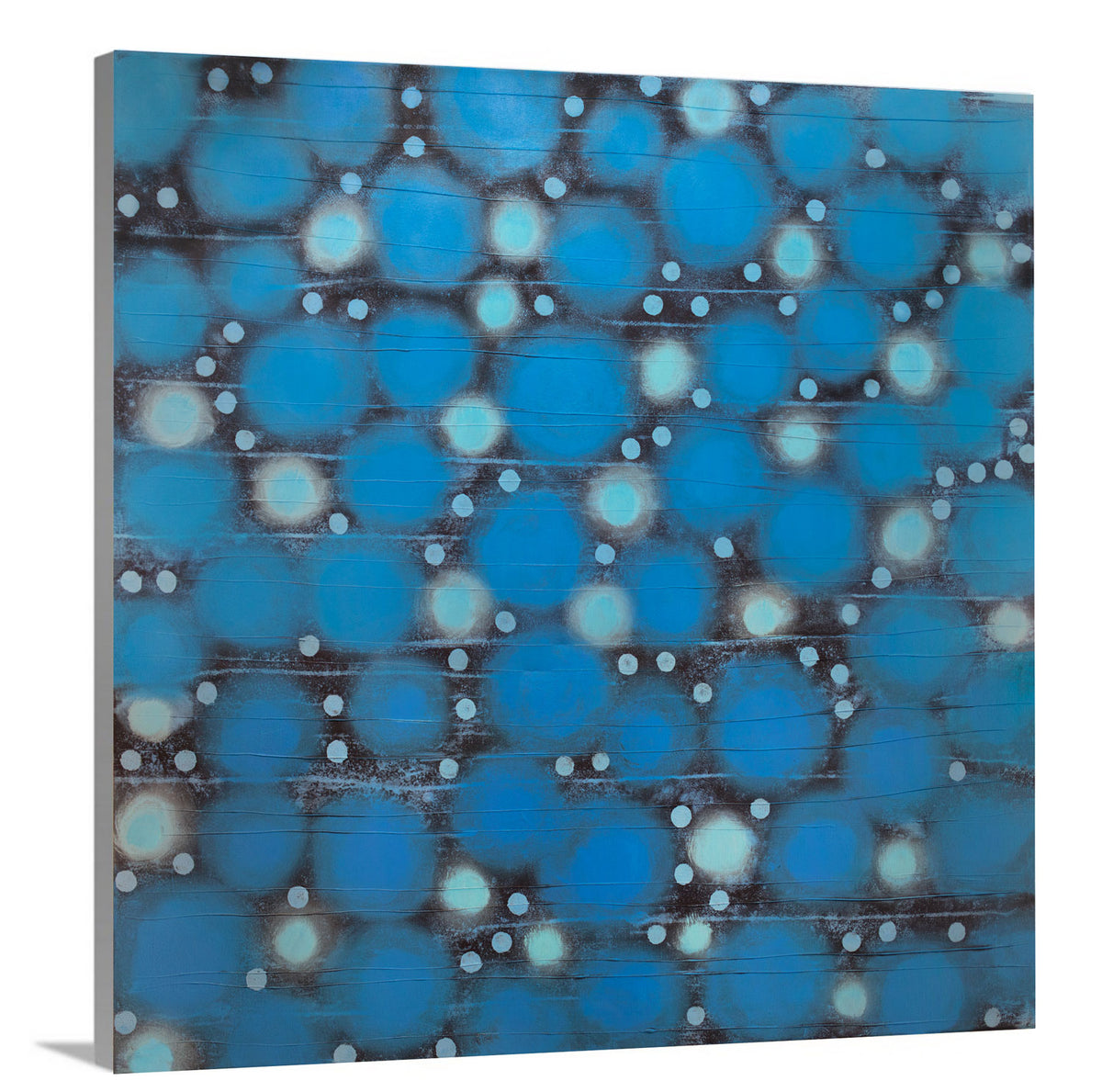 A side-angle view of a blue, teal and black abstract circle print on canvas.