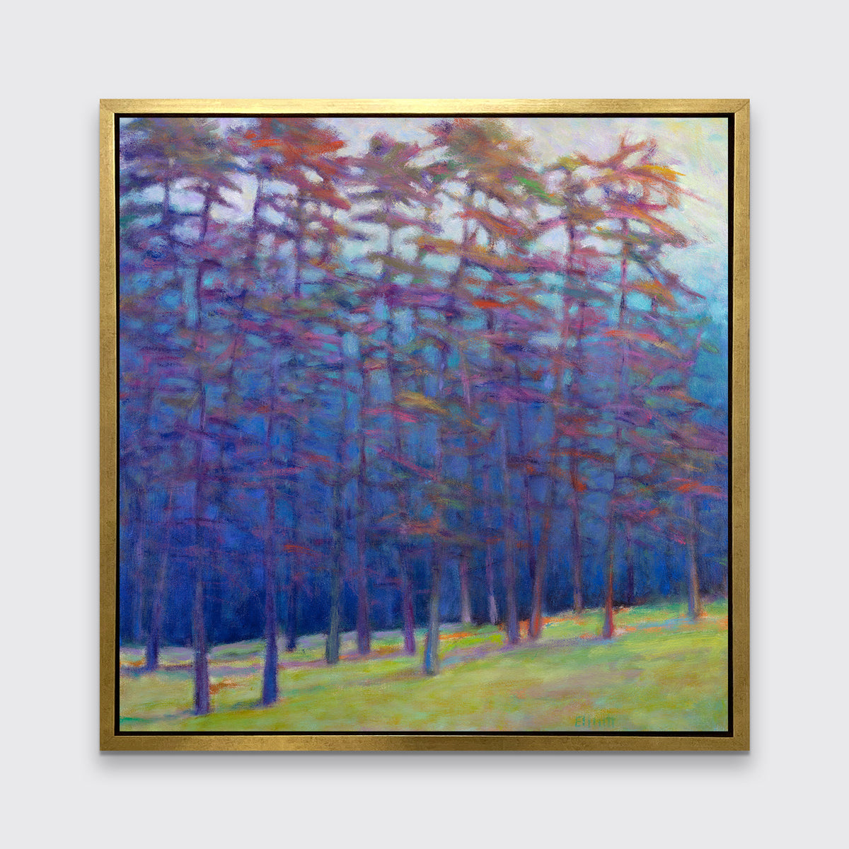 A blue, green, red and pink abstract landscape print in a gold floater frame hangs on a white wall.
