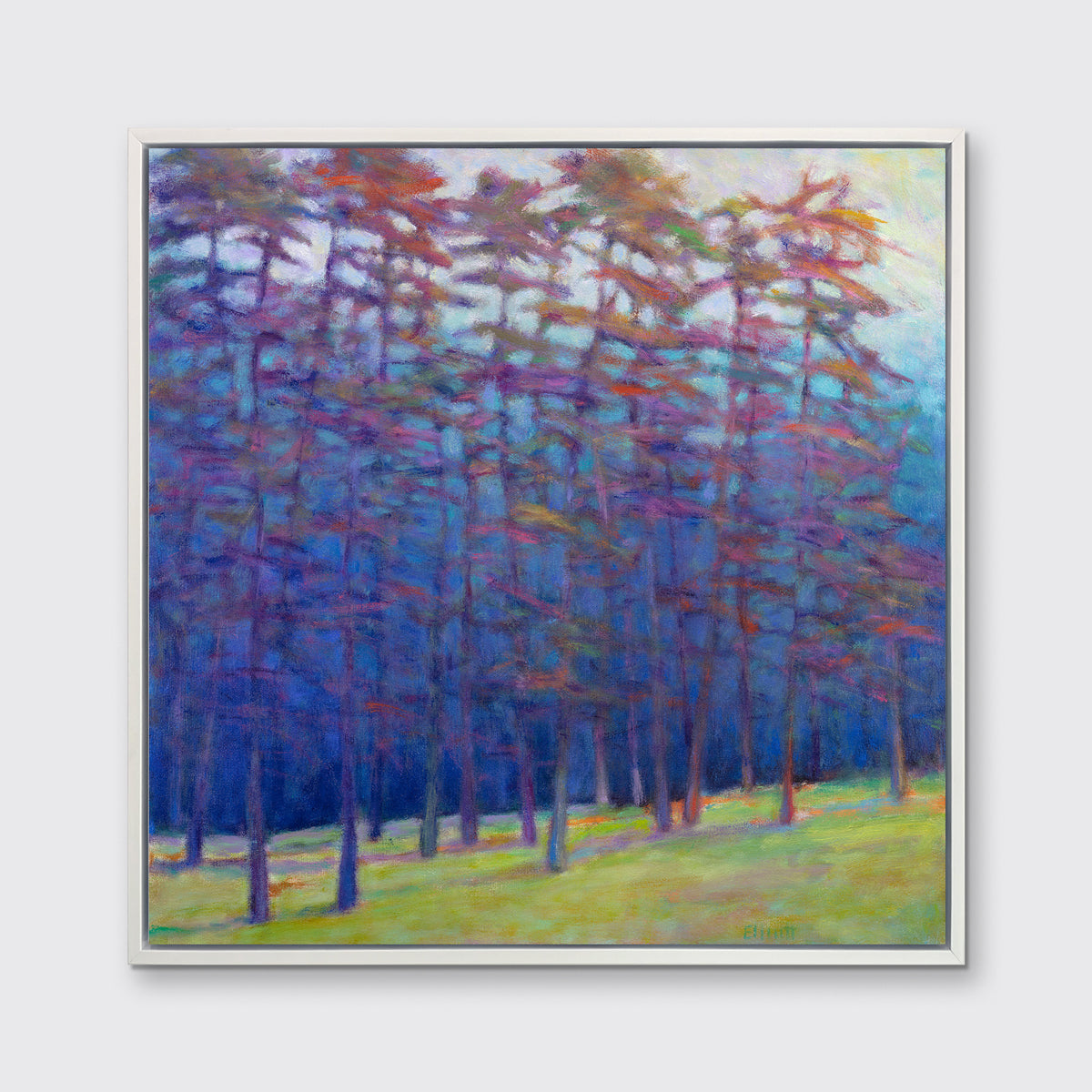 A blue, green, red and pink abstract landscape print in a white floater frame hangs on a white wall.