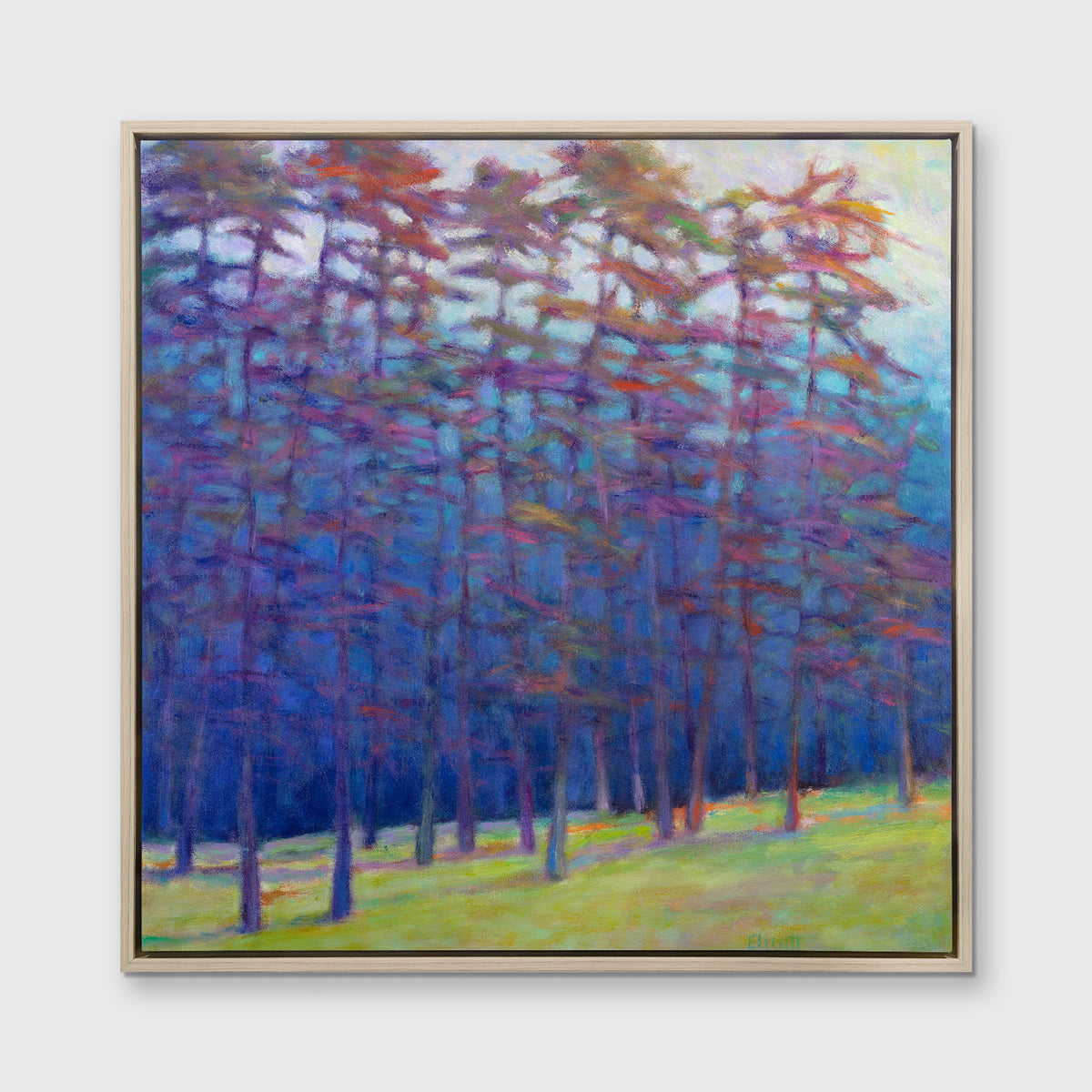A blue, green, red and pink abstract landscape print in a white oak wood floater frame hangs on a white wall.