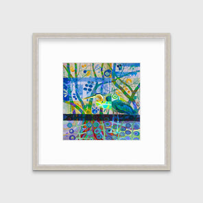 A multicolored abstract print of a bird in a silver frame with a mat hangs on a white wall.