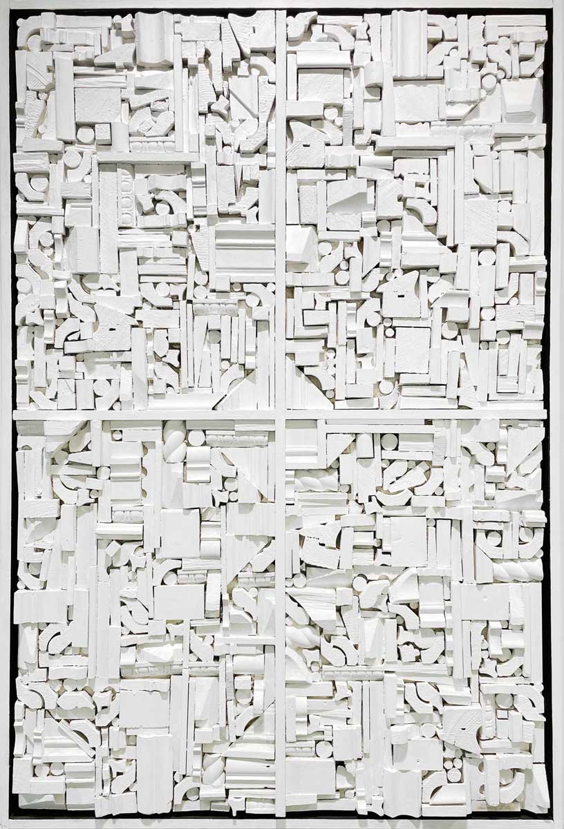 A white geometric abstract wood construction in a white floater frame.