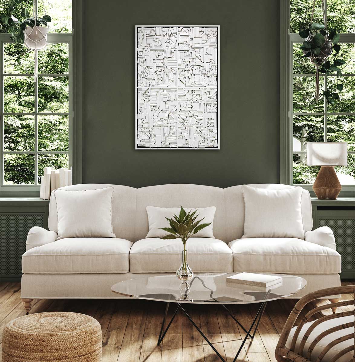 A white geometric abstract wood construction in a white frame hangs on a green wall above a white sofa with pillows and a glass round coffee table.