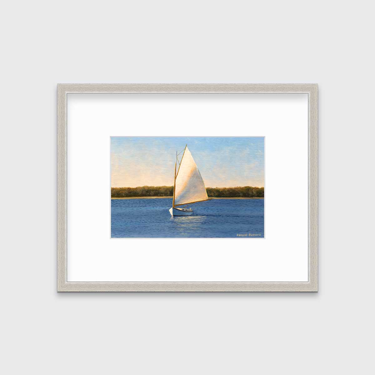 A blue and beige contemporary seascape print with a sailboat in a silver frame with a mat hangs on a white wall.