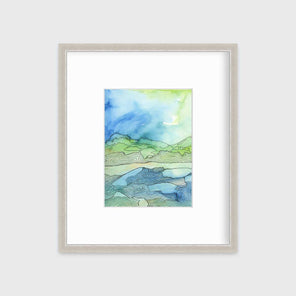 A green and blue abstract landscape illustration print in a silver frame with a mat hangs on a white wall.