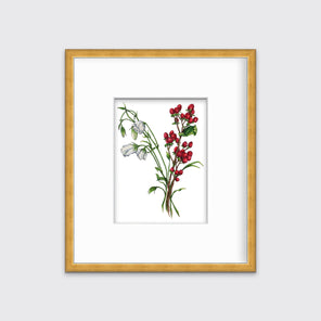 A print of white and red flowers hangs in a gold frame on a white frame. 