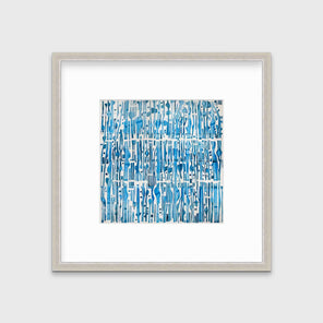 A blue and white abstract print in a silver frame with a mat hangs on a white wall.