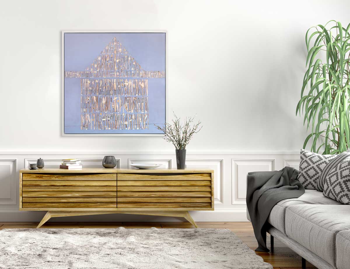 A lavender and beige abstract house print in a white floater frame hangs on a white wall above a low wooden console cabinet with grey accessories and across from a light grey sofa with a dark grey throw blanket.
