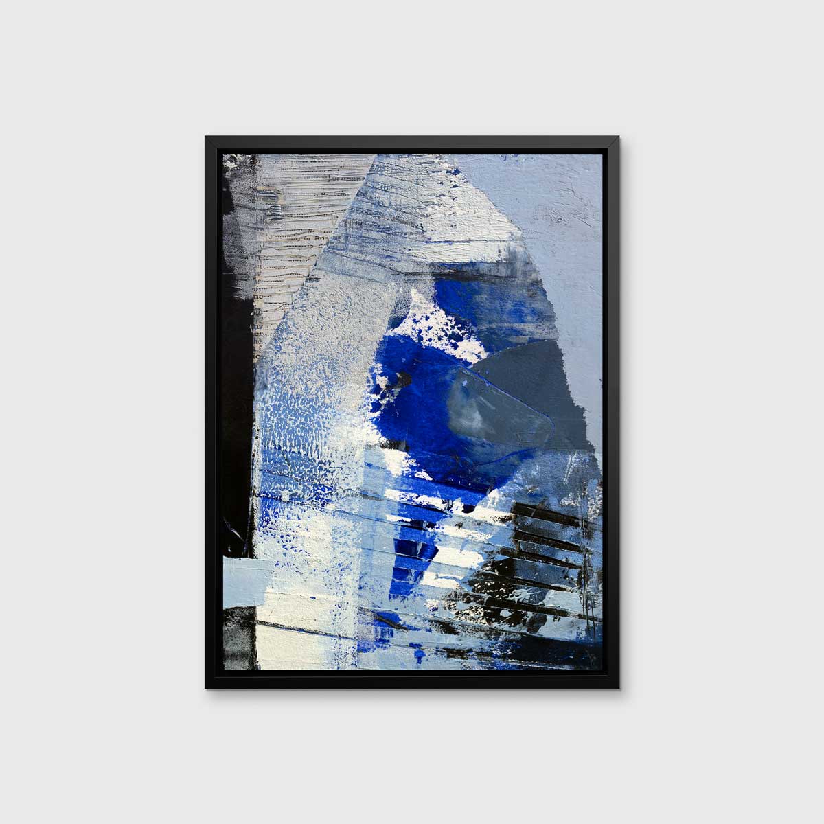 A blue, white and black abstract print in a black floater frame hangs on a white wall.