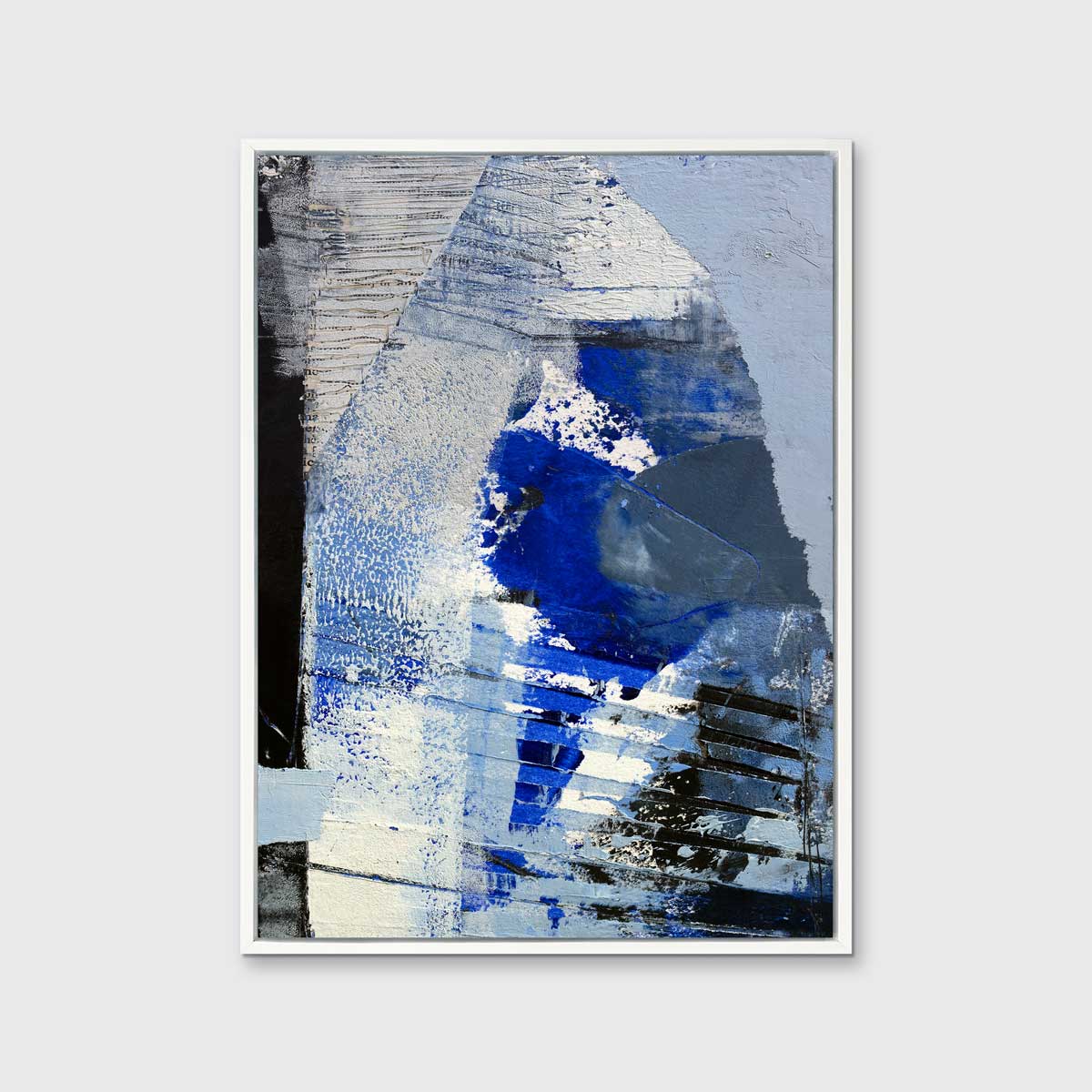 A blue, white and black abstract print in a white floater frame hangs on a white wall.