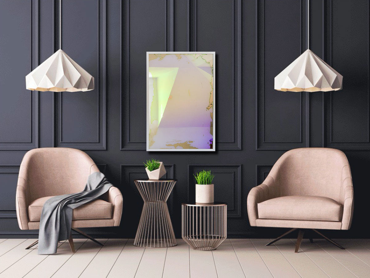 A pink, yellow and orange dichroic film art mirror in a white frame hangs vertically on a charcoal paneled wall above two blush pink chairs and two wire side tables with small potted plants.