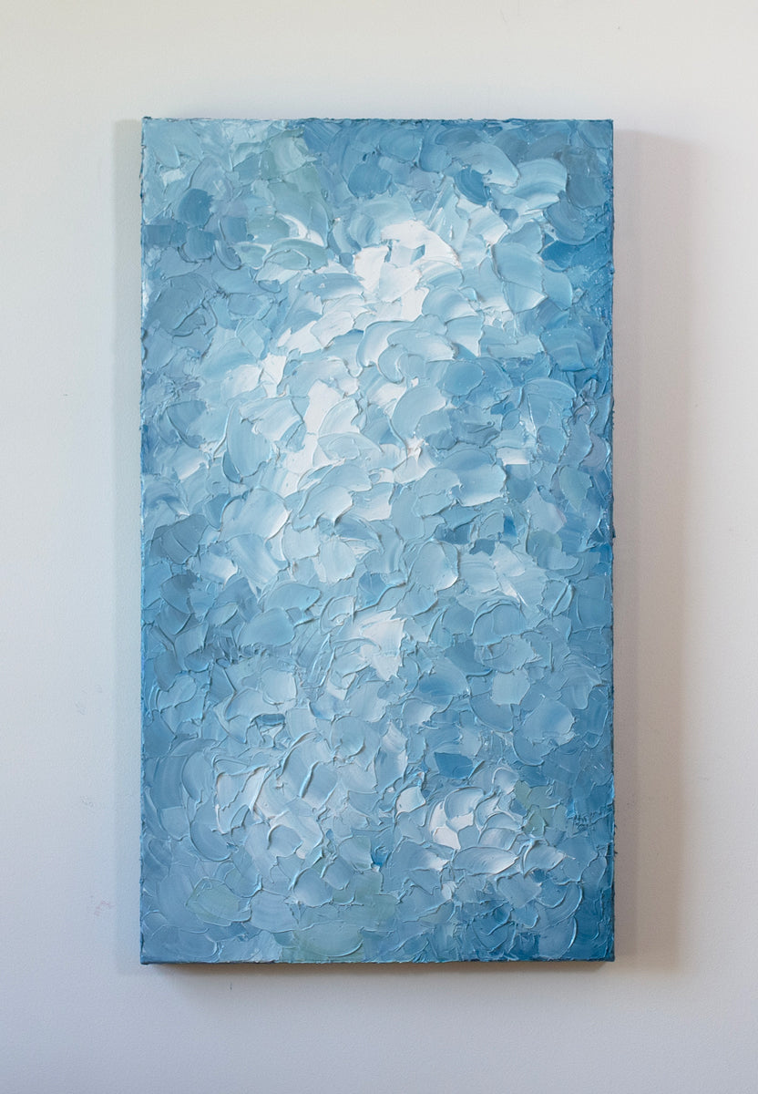 A blue and white abstract painting by Teodora Guererra hangs vertically on a white wall.