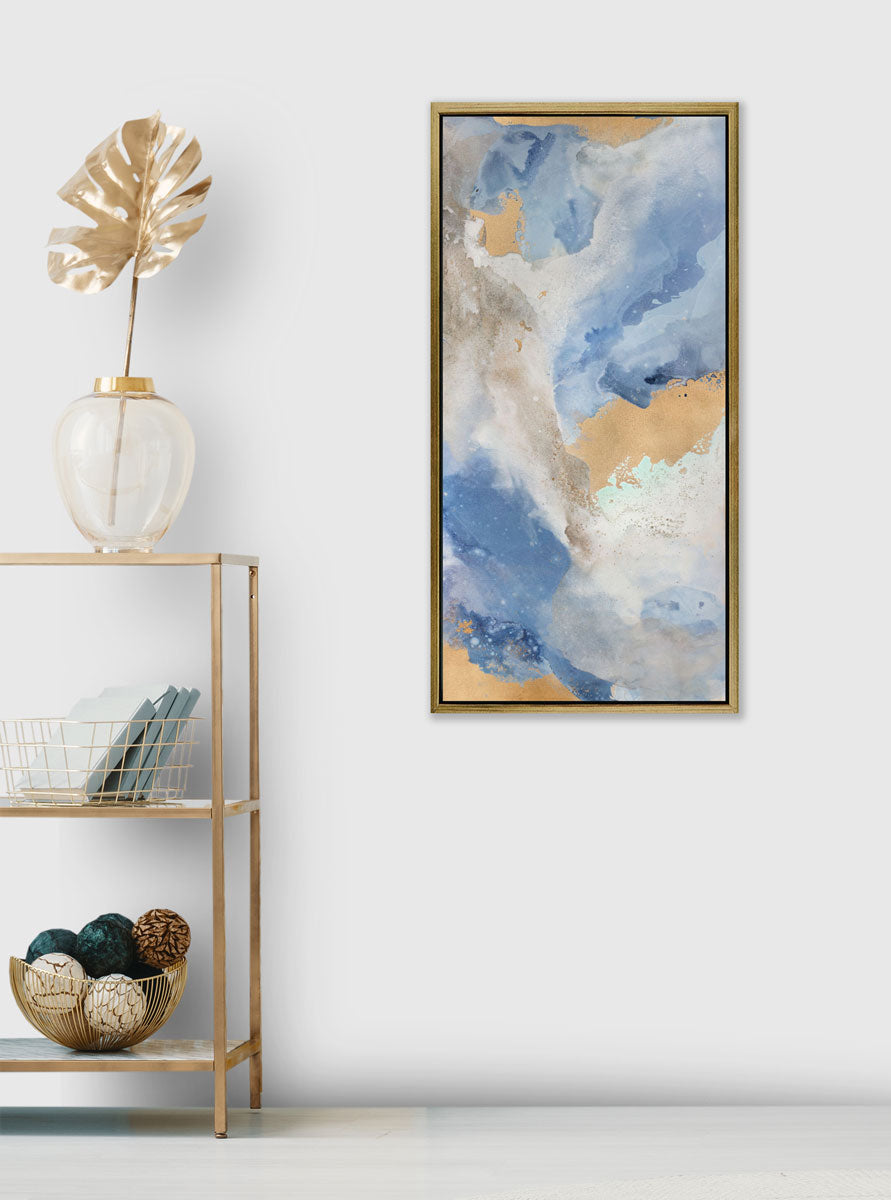 An abstract print by Julia Contacessi hangs on a white wall next to a gold console shelving unit with gold decor accessories. 