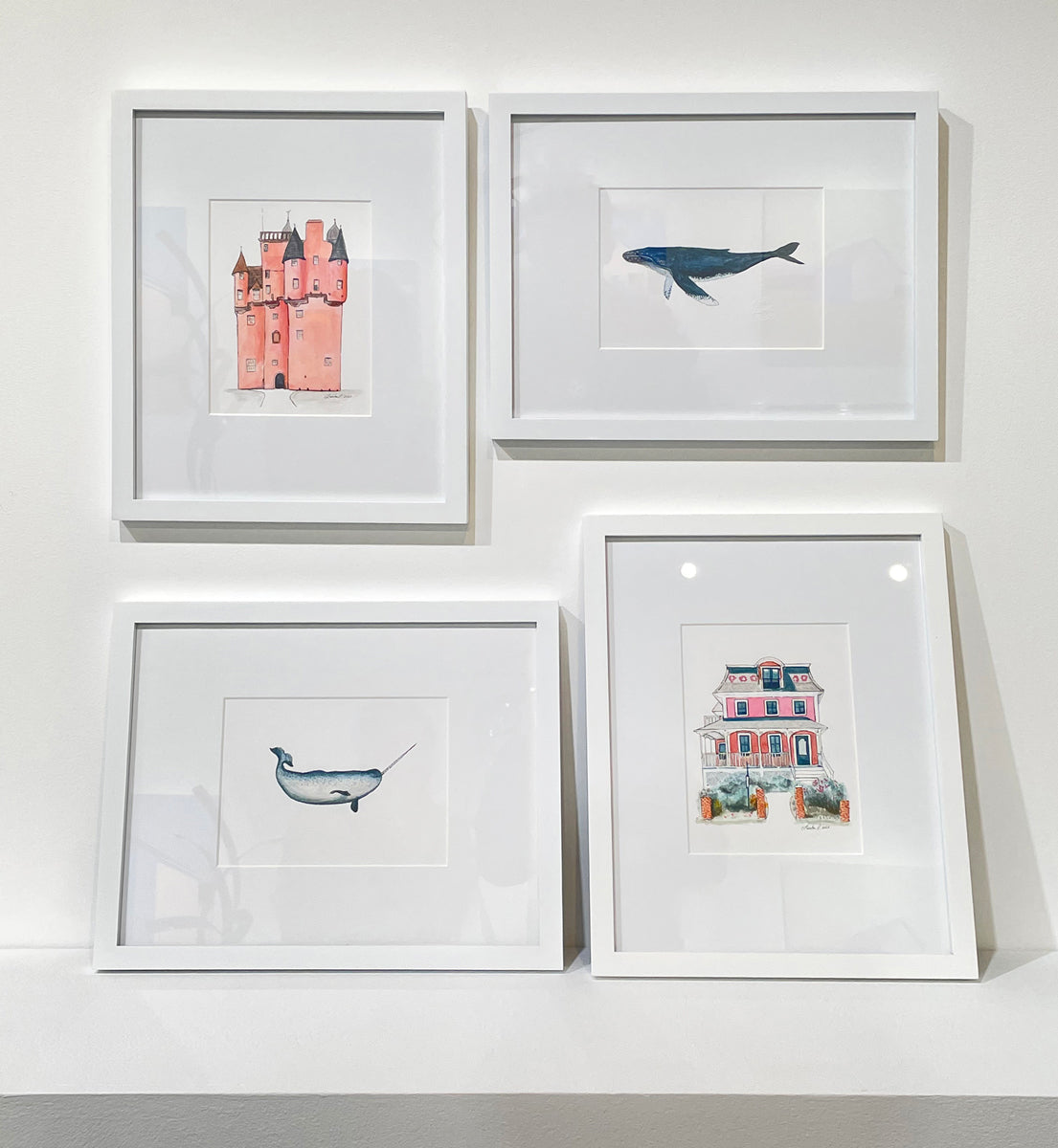 Four minimalistic watercolor paintings by Laerta Premto matted and framed in white frames rest against a white wall.