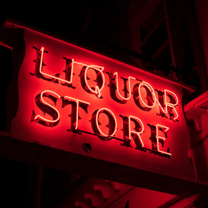 A photograph of a red neon sign on the side of a building which reads "liquor store". 