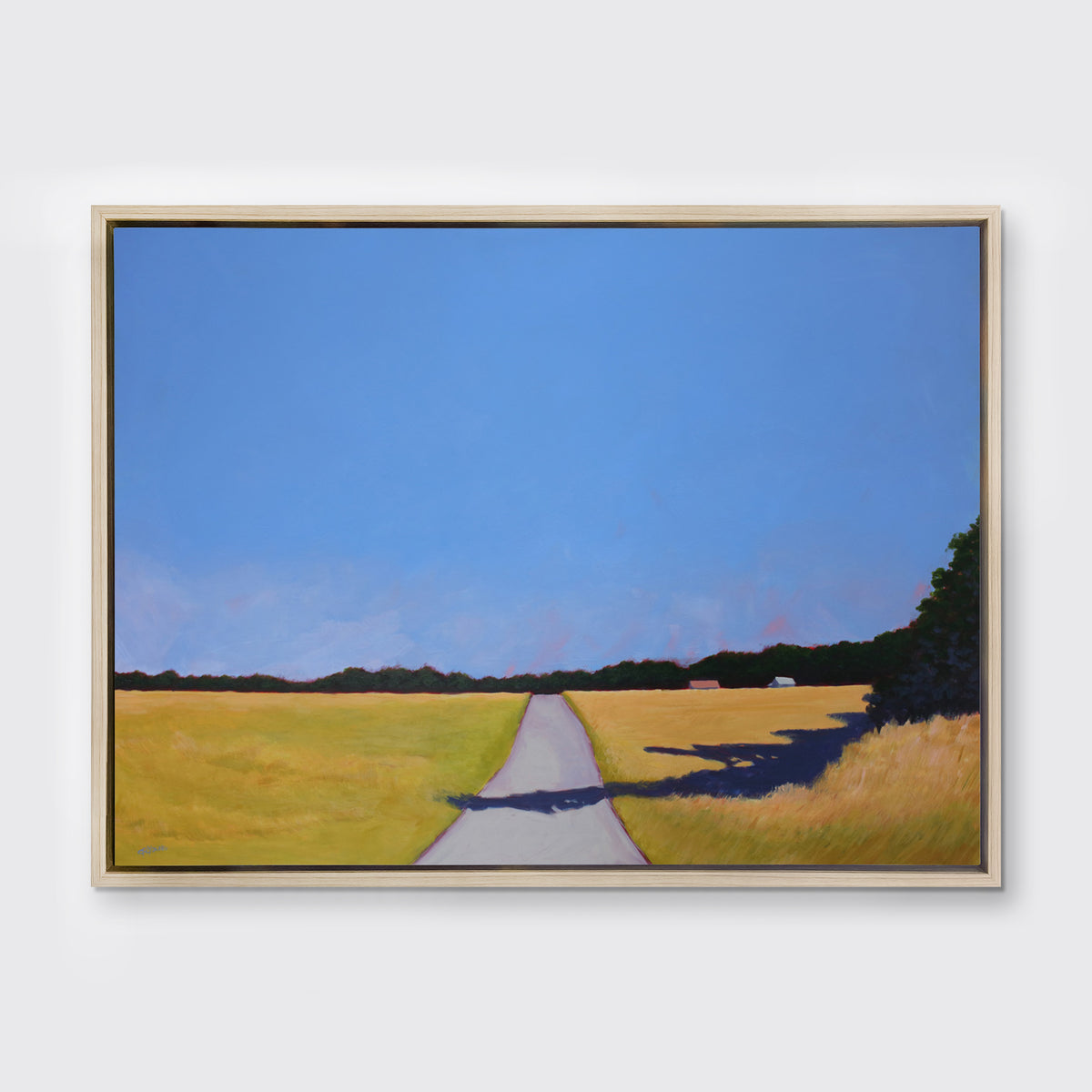 A blue and yellow-green abstract landscape print, framed in a white oak frame hangs on a light wall. 