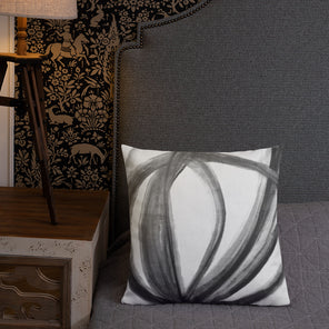 A square throw pillow of Mary Gaspar's painting, Tulip Cell, on a grey bed and next to a wood lamp.
