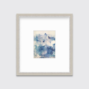 A blue abstract print matted and framed in a silver frame hangs on a white wall. 