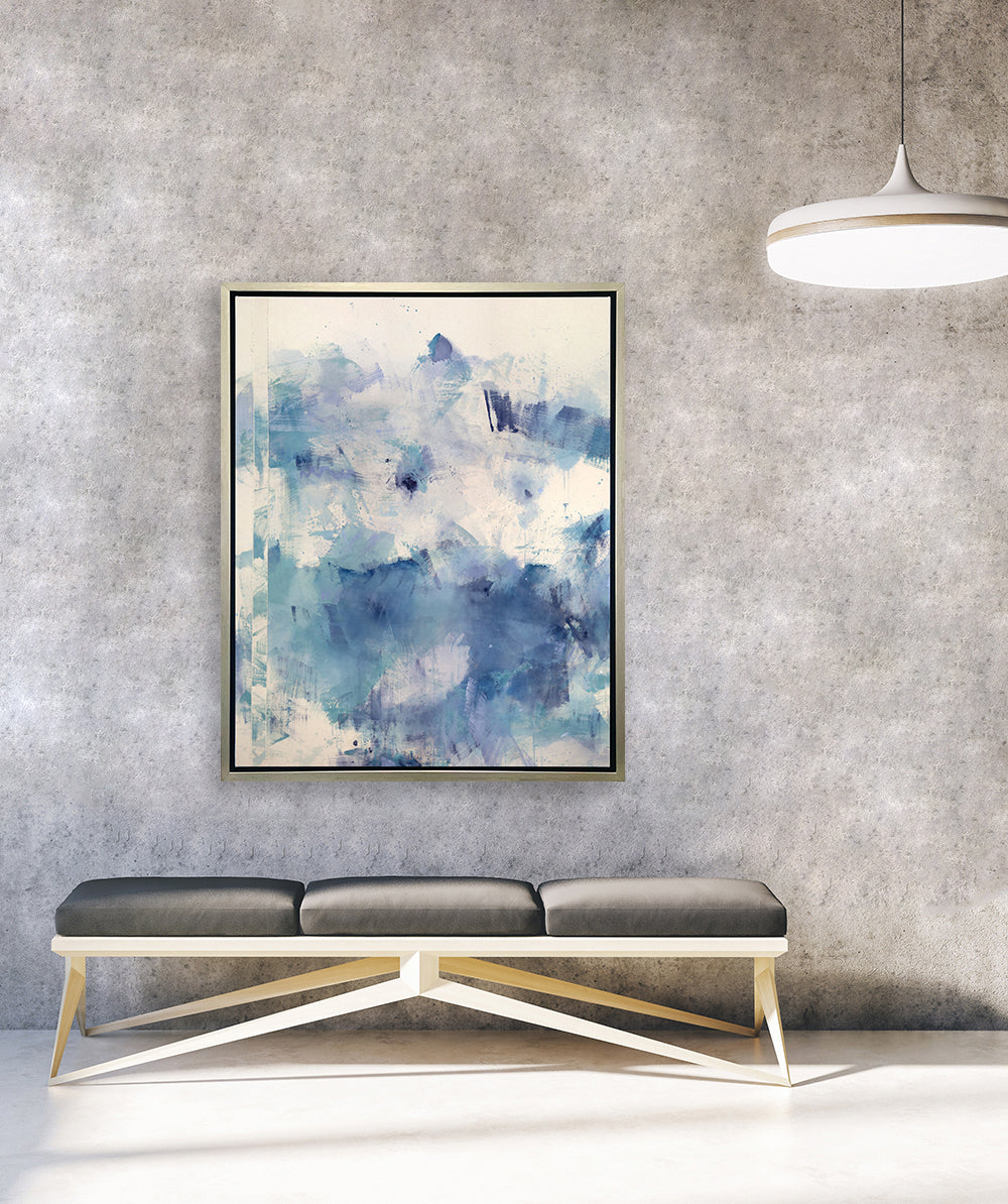 A blue, purple, and white abstract print framed in a silver frame hangs on a grey concrete wall above a modern bench. 