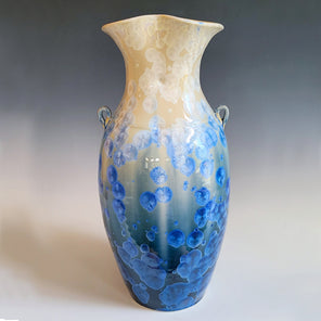 A beige and blue ceramic vessel with a crystalline glaze. 