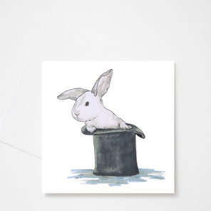 A white greeting card with an illustration of a white rabbit in a black top hat displayed above a white envelope on a white background.