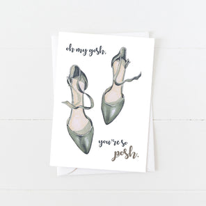 A white greeting card with an illustration of the tops of high heels with text displayed above a white envelope on a white background. 