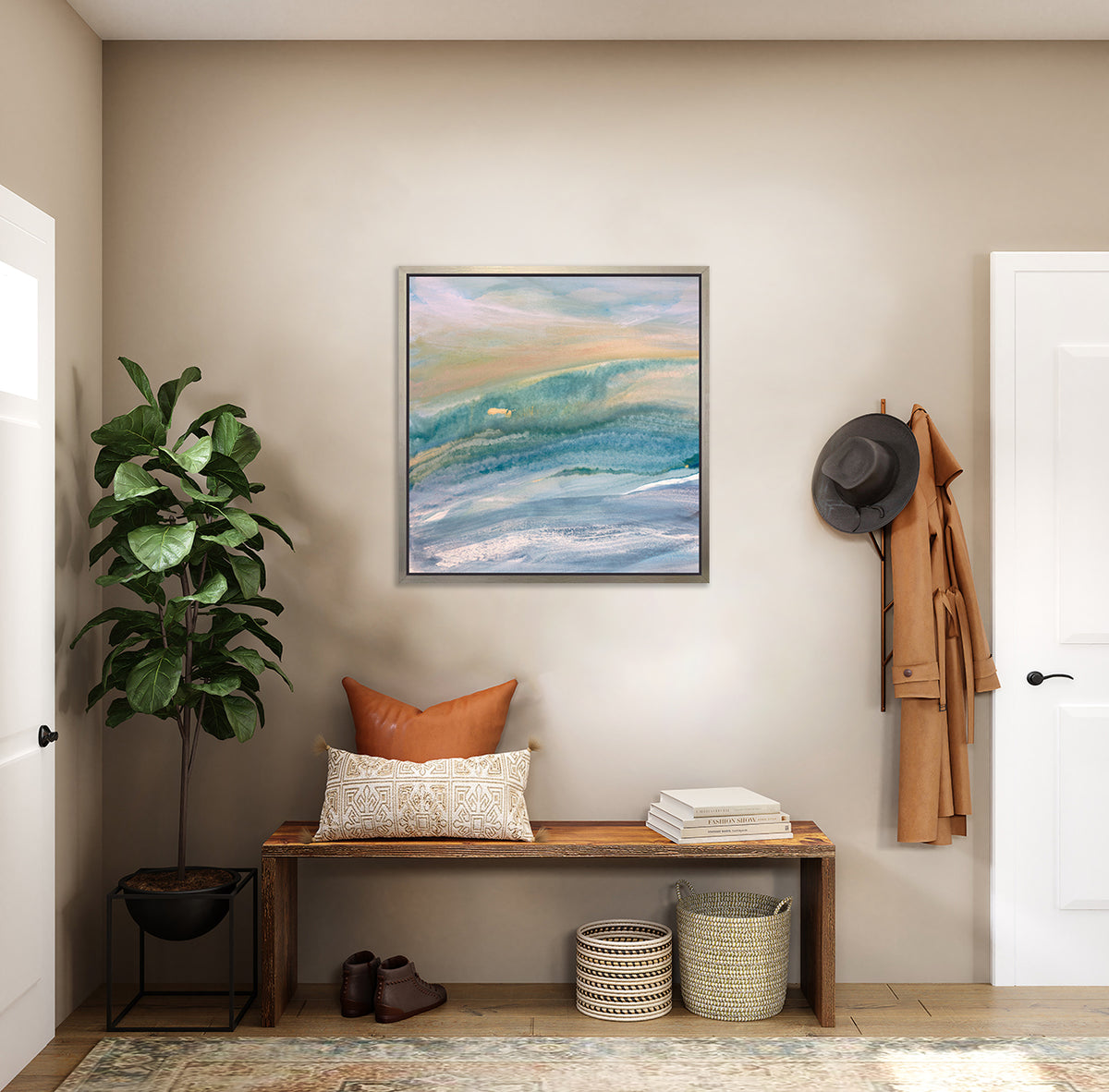 A blue, teal, yellow and white abstract print in a silver floater frame hangs on a white wall above a live edge bench with neutral pillows, a stack of books and two woven baskets.
