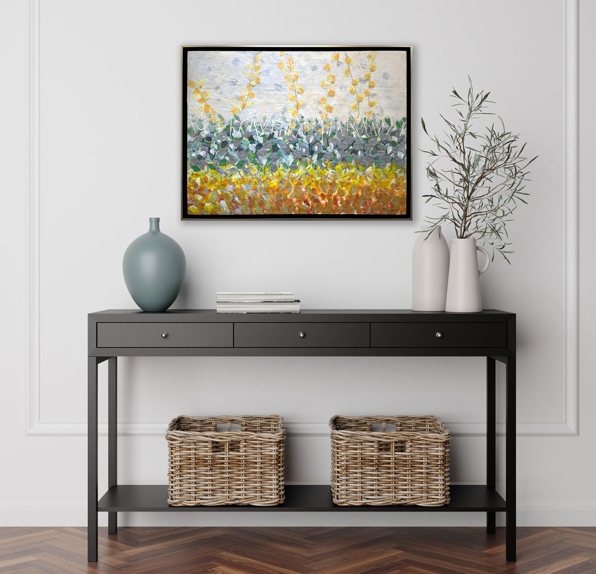 An abstract encaustic painting of gold and silver flowers is hung above a black console table..