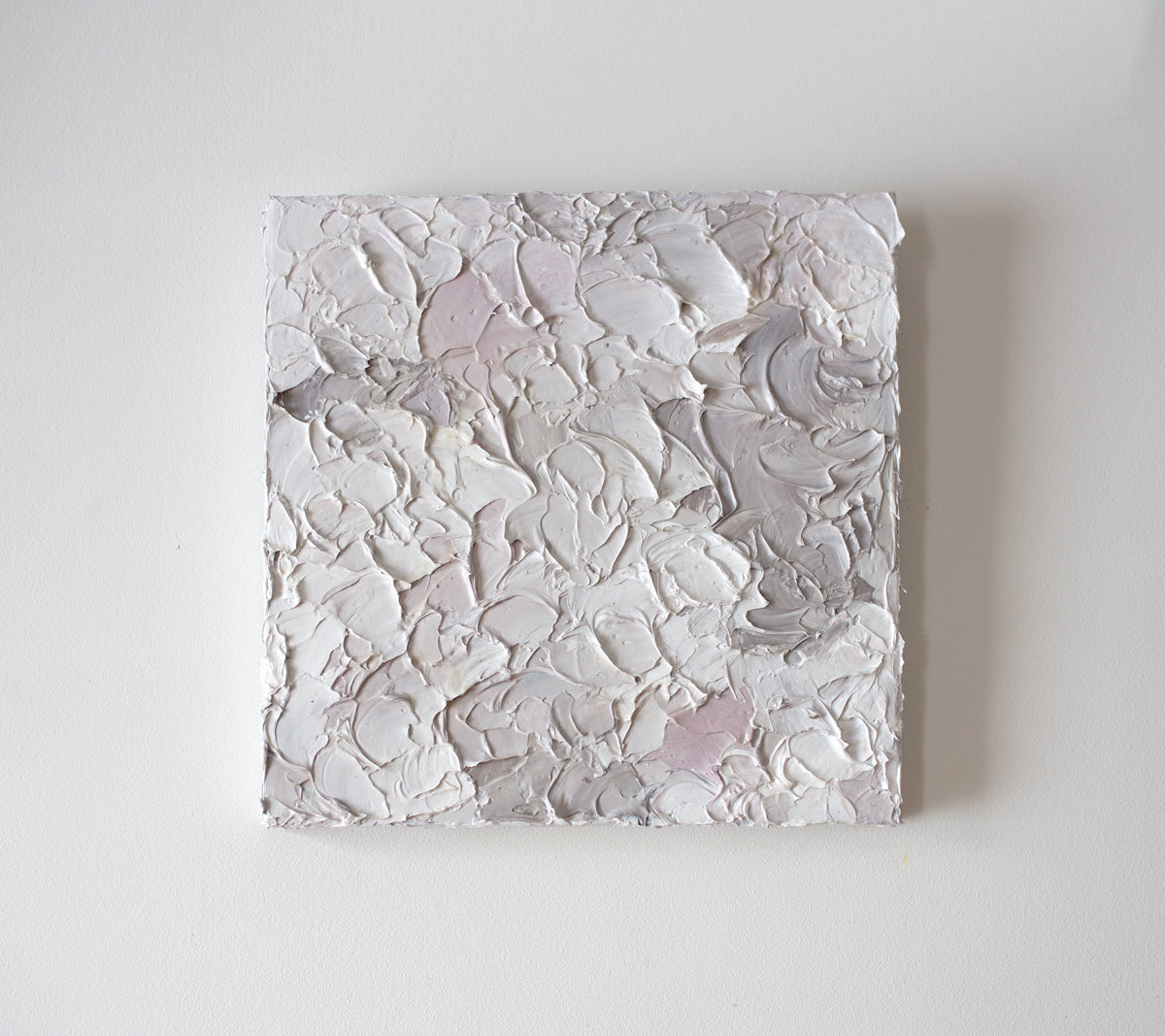 A light pink, white and warm grey impasto abstract painting. Hangs on a white gallery wall.