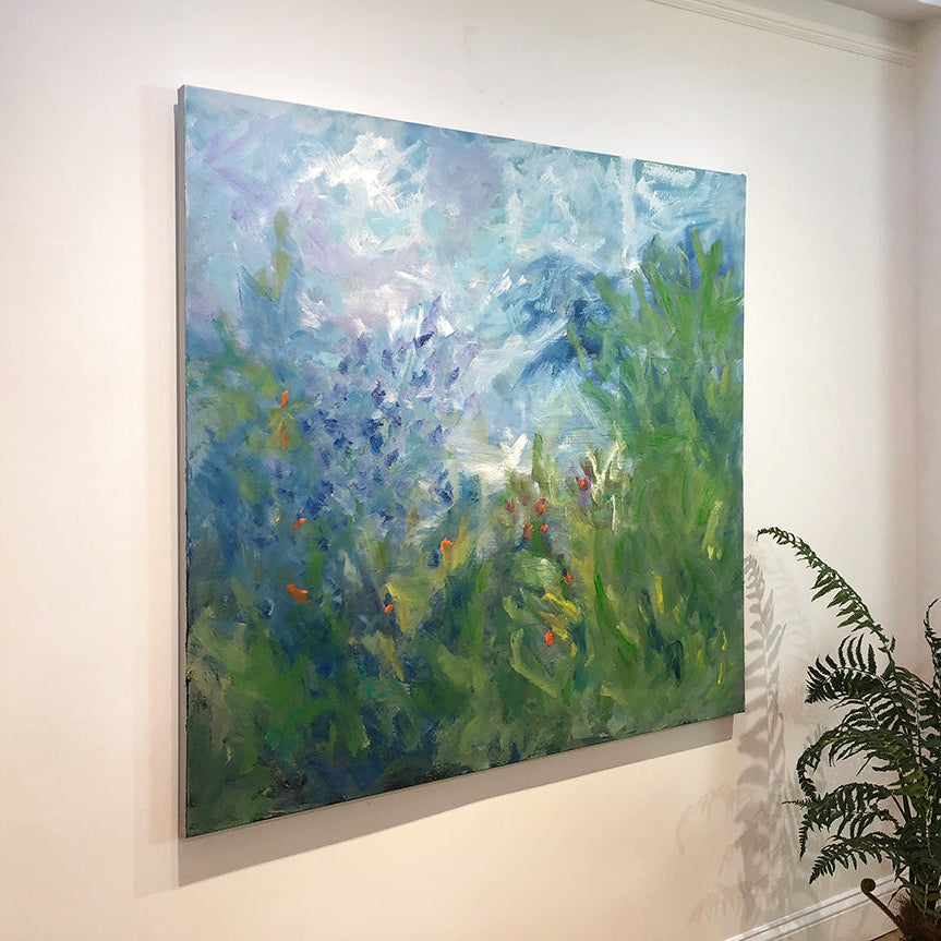 Painting of a floral landscape with blue sky, green fields, and flowers on a white wall.