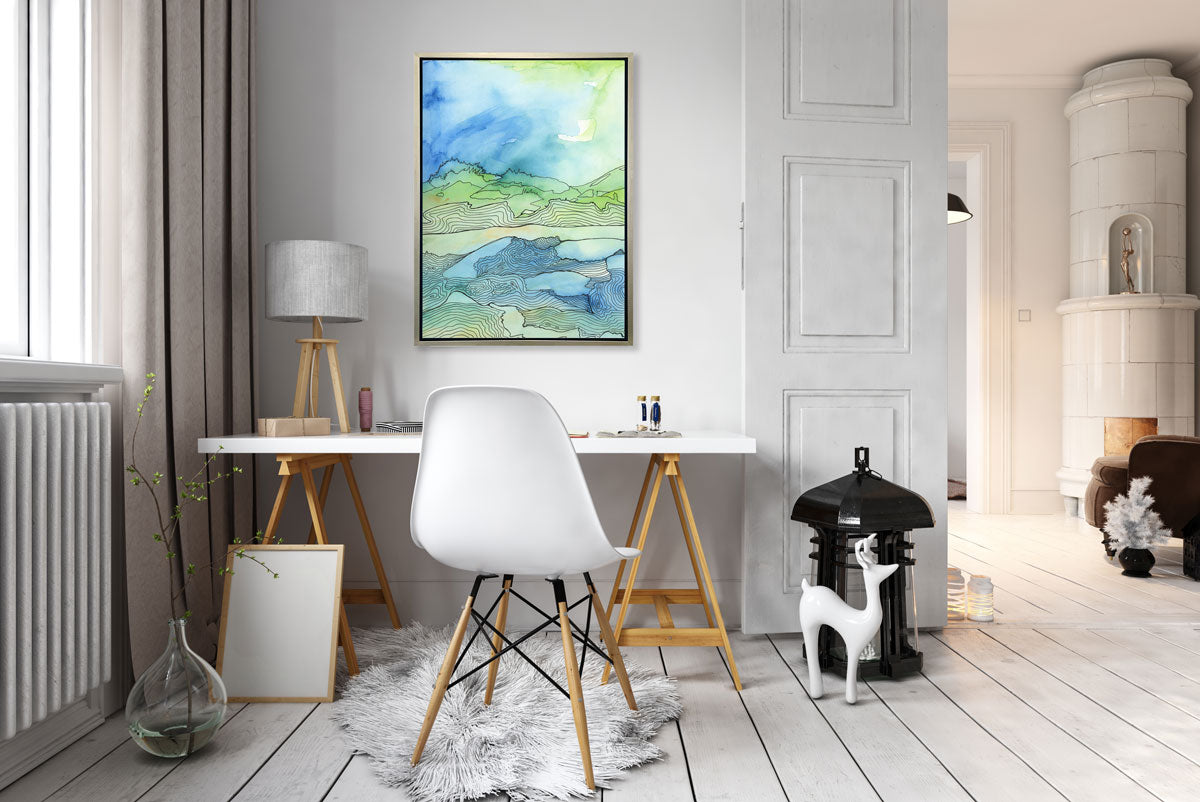 A blue and green abstract canvas print hangs above a minimalist desk next to a window. 
